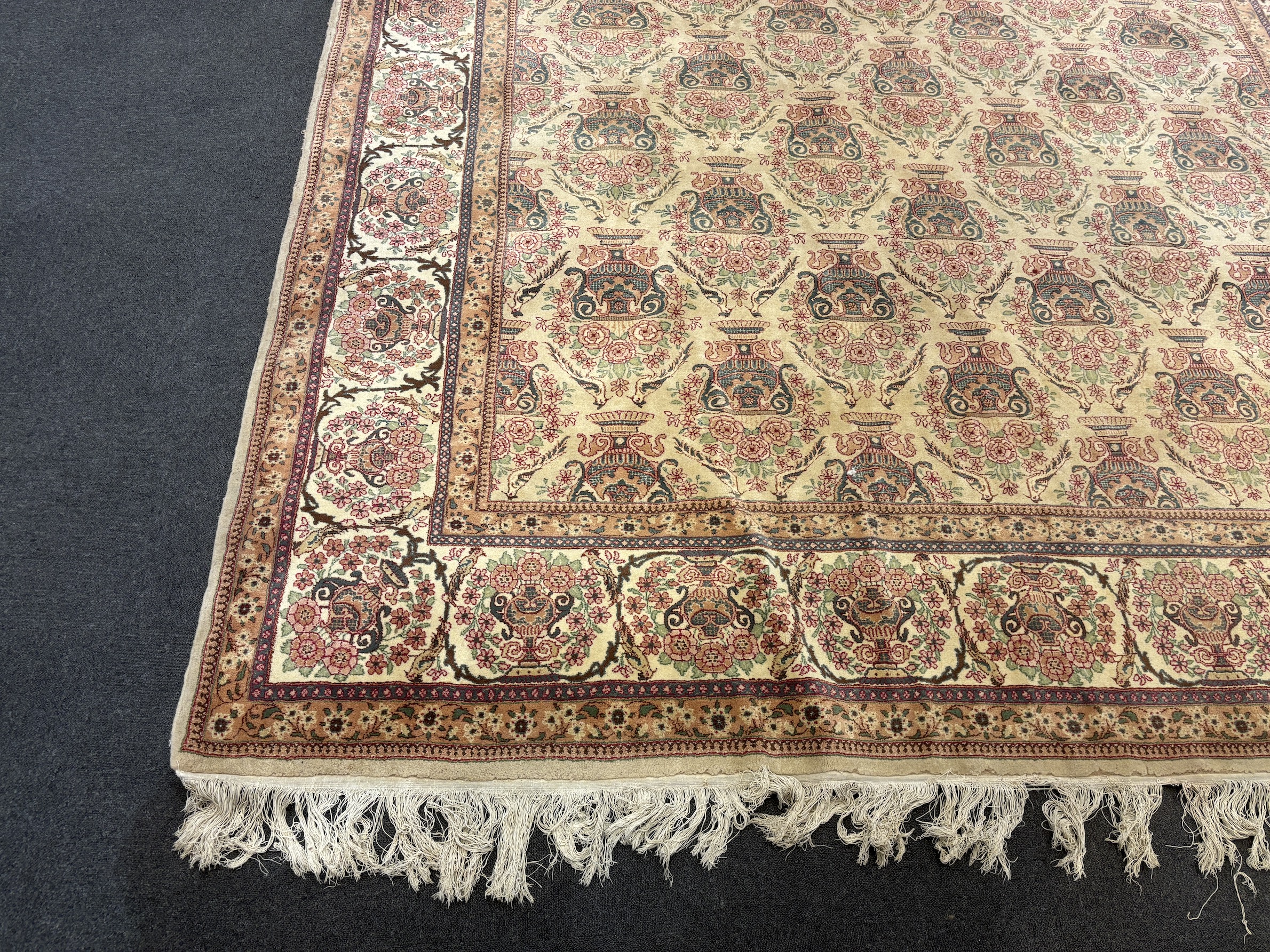 A North West Persian ivory ground carpet, woven with rows of flowering urns, 400 x 298cm